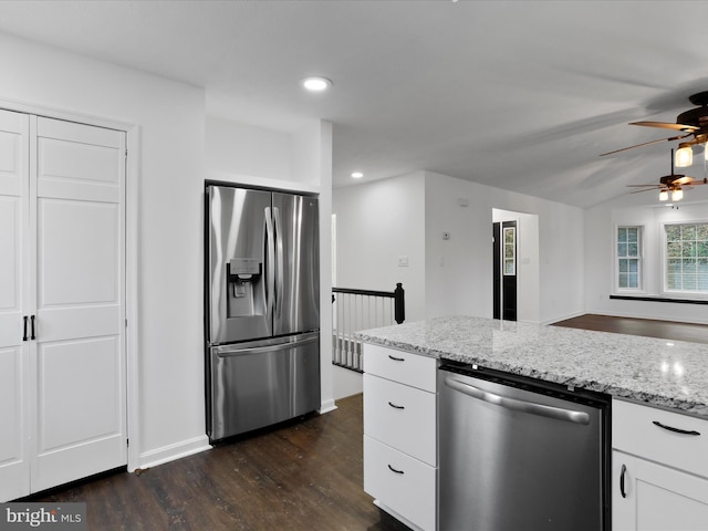 kitchen with light stone countertops, white cabinetry, dark wood-type flooring, and appliances with stainless steel finishes