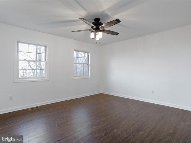 empty room with dark hardwood / wood-style floors, plenty of natural light, and ceiling fan