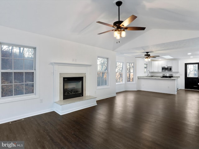 unfurnished living room featuring dark hardwood / wood-style flooring, ceiling fan, lofted ceiling, and sink