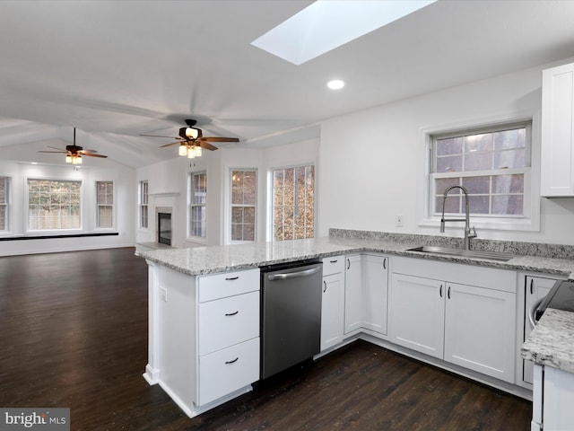 kitchen featuring lofted ceiling with skylight, dishwasher, white cabinets, and sink