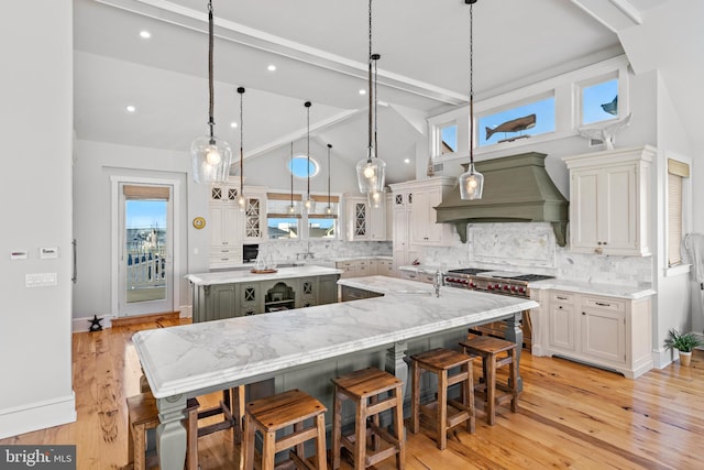 kitchen featuring custom range hood, a spacious island, high end stainless steel range, white cabinetry, and hanging light fixtures