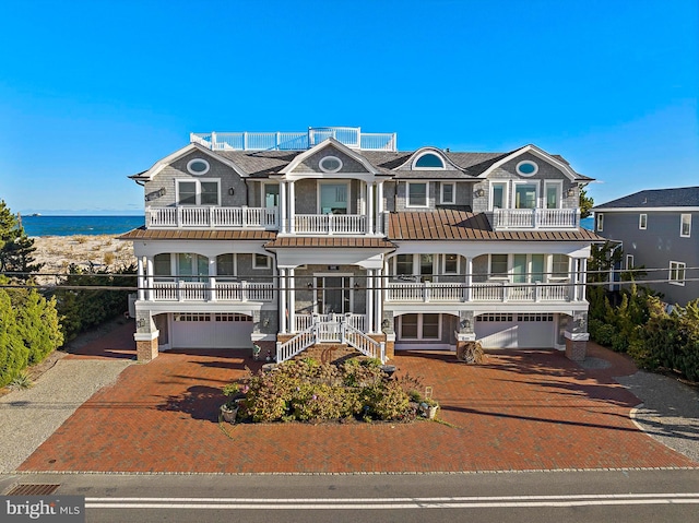 view of front of home with a garage, a balcony, and a water view