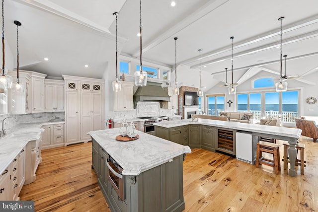 kitchen with a large island, white cabinets, pendant lighting, and high end stainless steel range oven