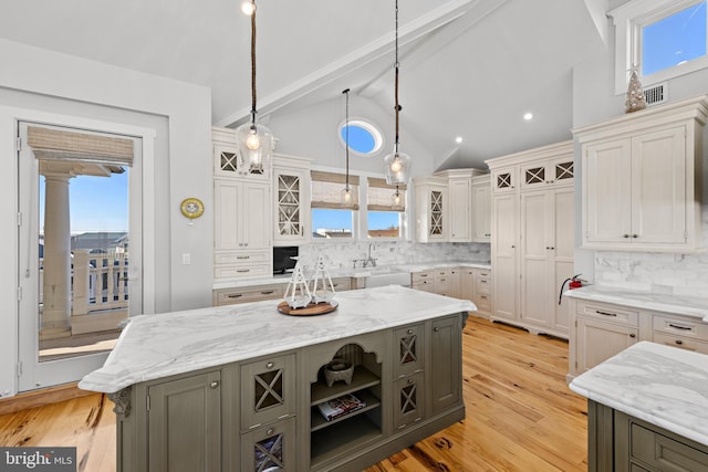 kitchen featuring backsplash, vaulted ceiling with beams, a center island, and hanging light fixtures