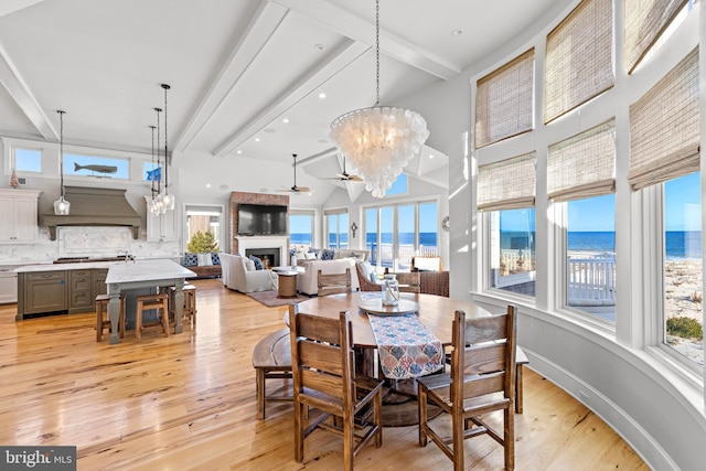 dining room featuring beamed ceiling, ceiling fan with notable chandelier, light hardwood / wood-style flooring, and sink