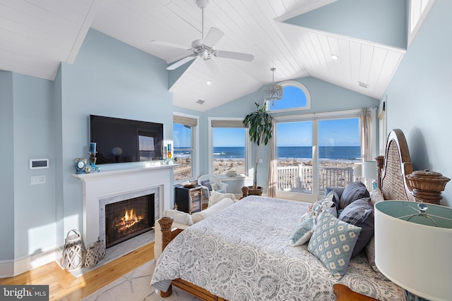 bedroom featuring multiple windows, ceiling fan, light hardwood / wood-style flooring, and a high end fireplace