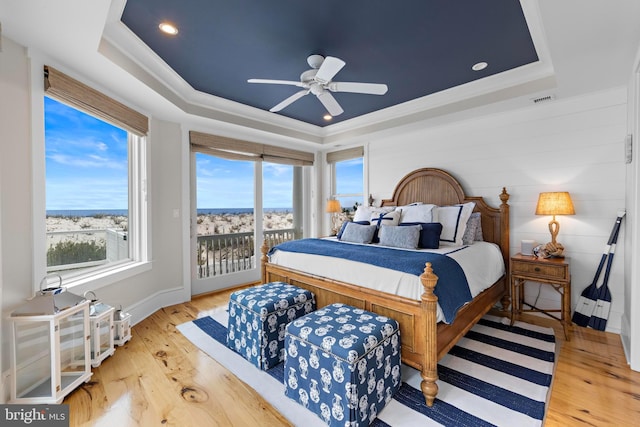 bedroom with a raised ceiling, ceiling fan, light hardwood / wood-style floors, and access to exterior