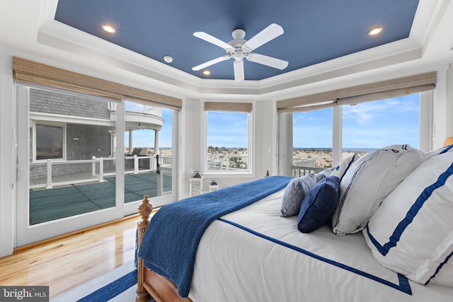 bedroom with hardwood / wood-style floors, ceiling fan, a raised ceiling, and access to outside