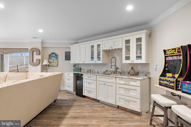 kitchen featuring white cabinetry, sink, light stone countertops, light wood-type flooring, and ornamental molding