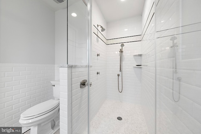 bathroom featuring an enclosed shower, toilet, and tile walls