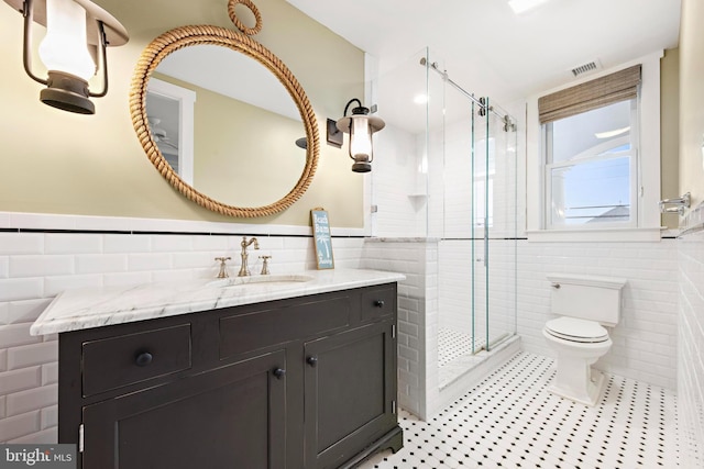 bathroom featuring vanity, a shower with shower door, tile walls, and toilet