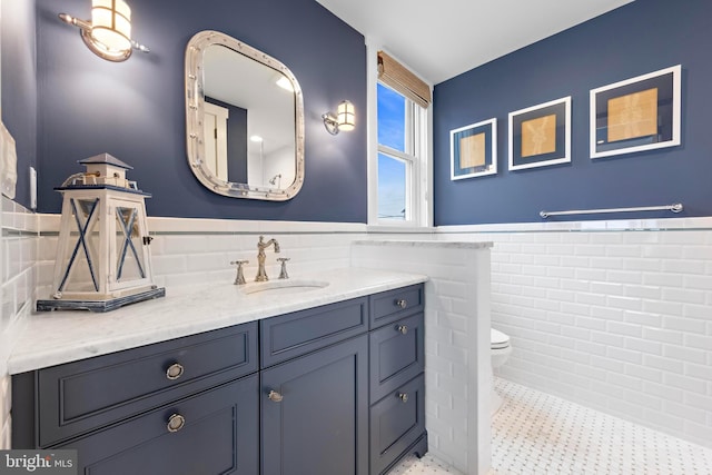 bathroom with tile patterned floors, vanity, toilet, and tile walls