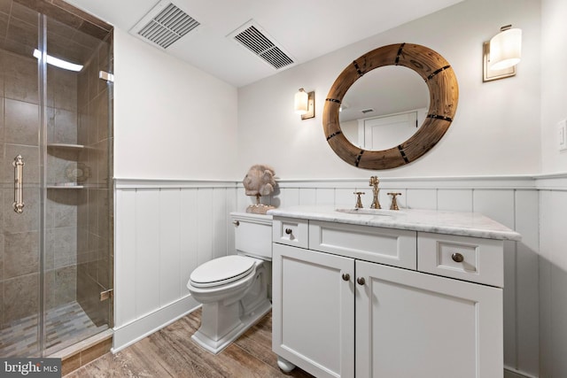 bathroom with hardwood / wood-style floors, vanity, toilet, and a shower with door