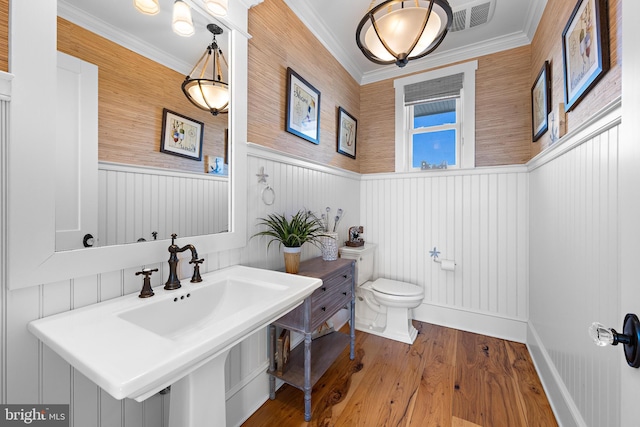 bathroom with wood-type flooring, toilet, and ornamental molding