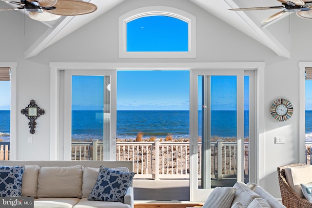 living room with ceiling fan, a healthy amount of sunlight, a water view, and a beach view