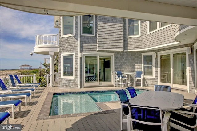 rear view of property with a swimming pool side deck and a balcony