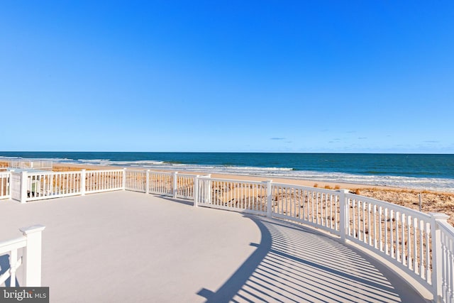 view of patio / terrace featuring a water view and a beach view