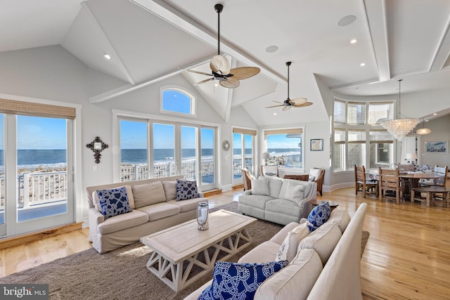 living room featuring ceiling fan with notable chandelier, a water view, high vaulted ceiling, and light hardwood / wood-style floors