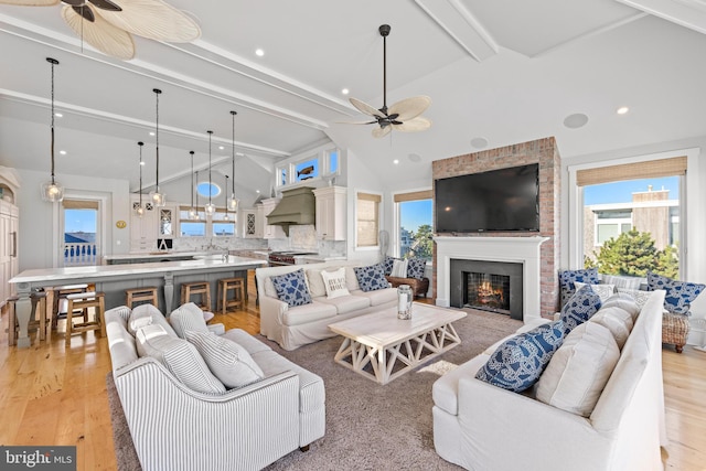 living room with beam ceiling, plenty of natural light, and light wood-type flooring