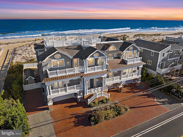 aerial view at dusk with a view of the beach and a water view