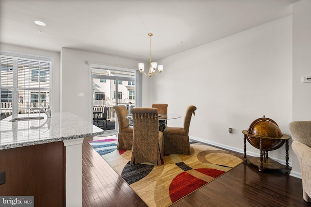 dining room with a chandelier, sink, and dark wood-type flooring