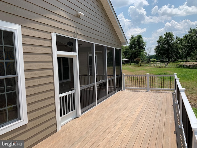 wooden terrace featuring a lawn and a sunroom