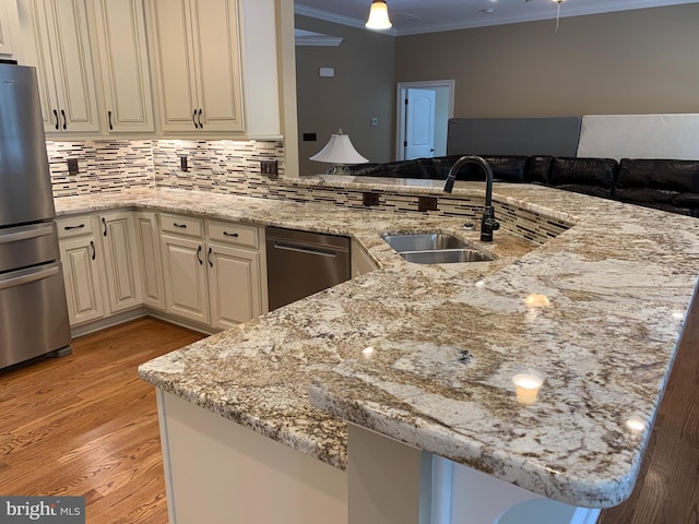 kitchen featuring kitchen peninsula, appliances with stainless steel finishes, light hardwood / wood-style floors, and ornamental molding