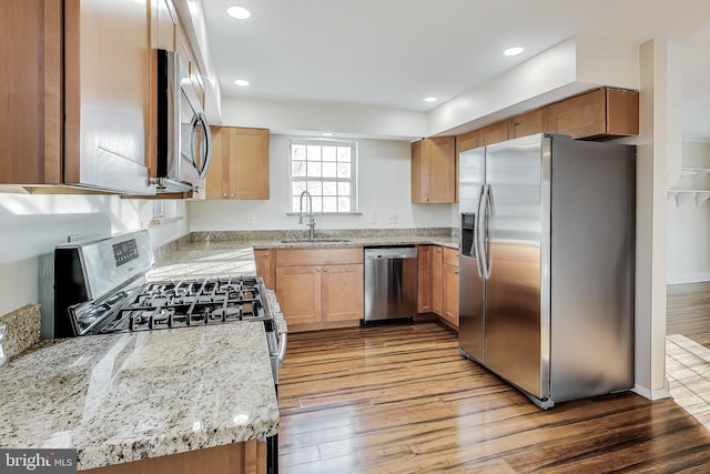 kitchen featuring light stone countertops, hardwood / wood-style floors, stainless steel appliances, and sink