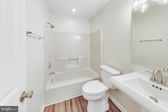 full bathroom with washtub / shower combination, hardwood / wood-style floors, toilet, and sink