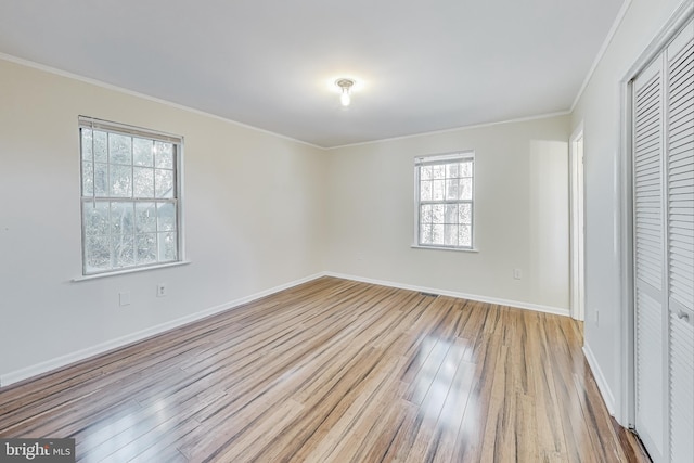 unfurnished bedroom featuring light wood-type flooring, multiple windows, and crown molding