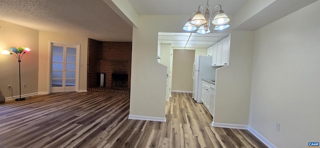 interior space with a textured ceiling, a fireplace, a chandelier, and dark hardwood / wood-style floors