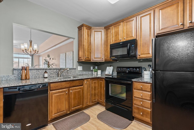 kitchen featuring light stone counters, sink, a notable chandelier, and black appliances