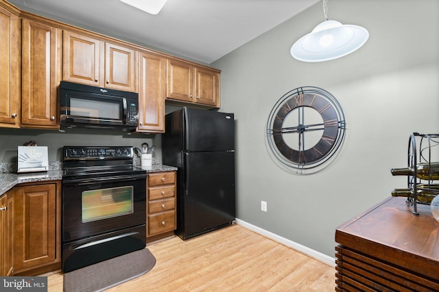 kitchen with light stone countertops, light hardwood / wood-style floors, and black appliances