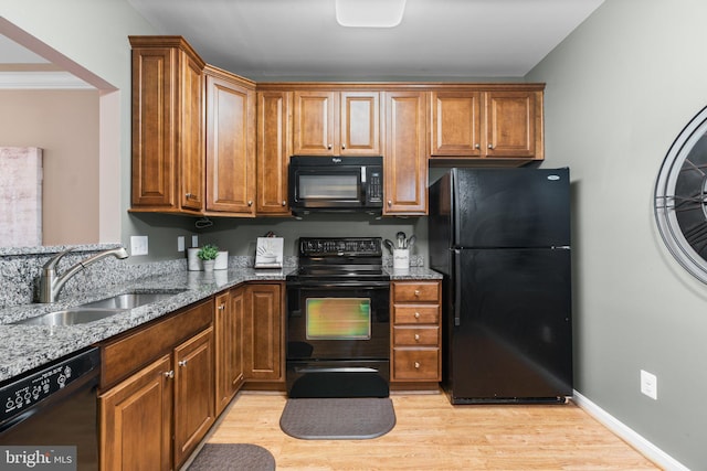 kitchen with stone counters, sink, light hardwood / wood-style flooring, and black appliances