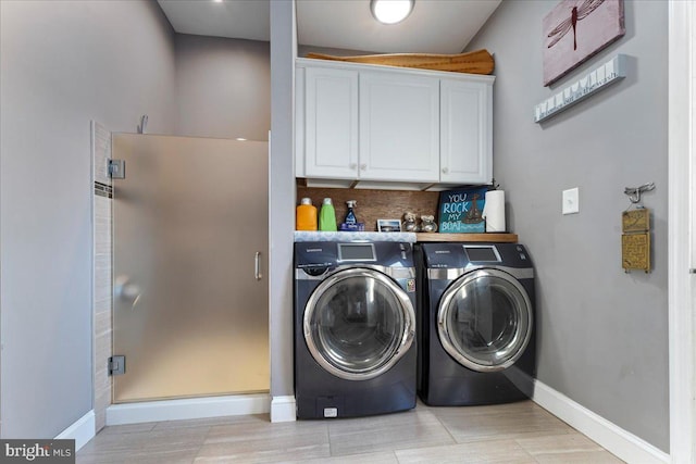 laundry area with washing machine and clothes dryer and cabinets