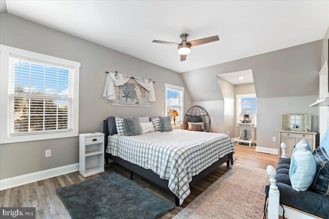 bedroom featuring hardwood / wood-style floors, multiple windows, lofted ceiling, and ceiling fan