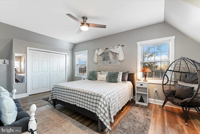 bedroom featuring hardwood / wood-style floors, ceiling fan, a closet, and multiple windows