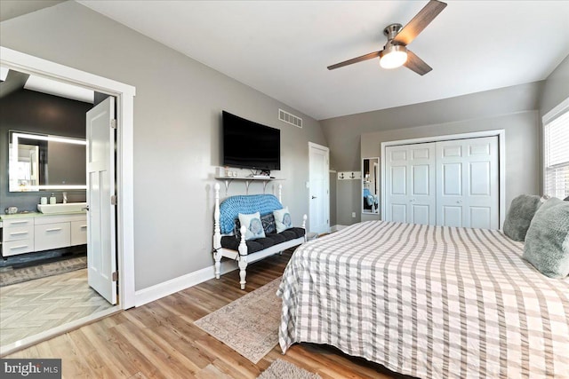 bedroom with sink, vaulted ceiling, ceiling fan, light wood-type flooring, and a closet