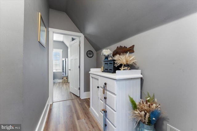 hallway featuring light wood-type flooring and vaulted ceiling