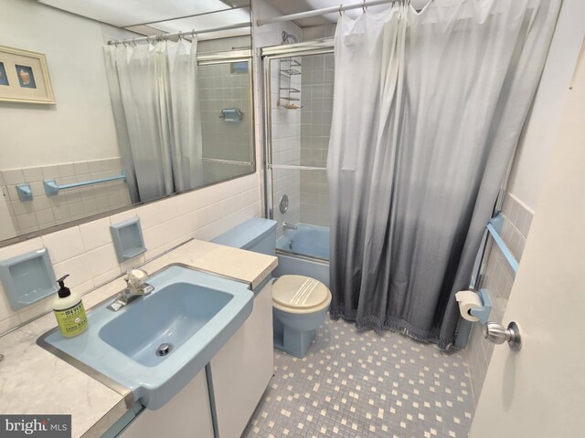 full bathroom featuring sink, tile patterned flooring, shower / bath combination with curtain, toilet, and tile walls