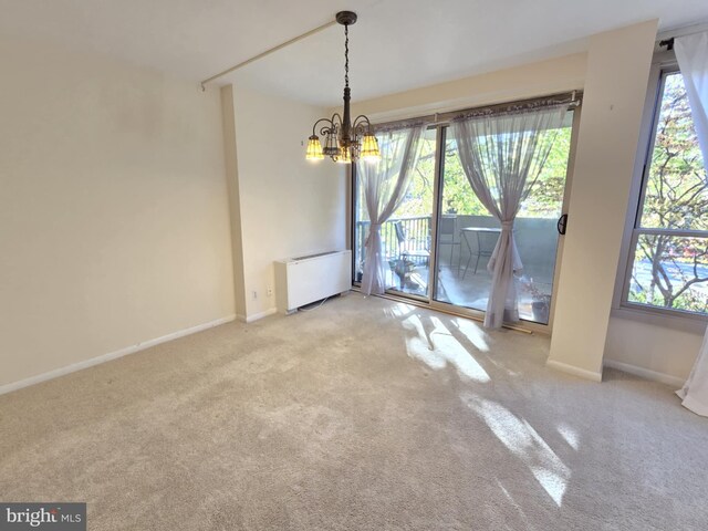 unfurnished dining area featuring plenty of natural light, light colored carpet, radiator, and a chandelier