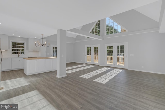 unfurnished living room featuring plenty of natural light, an inviting chandelier, and light wood-type flooring