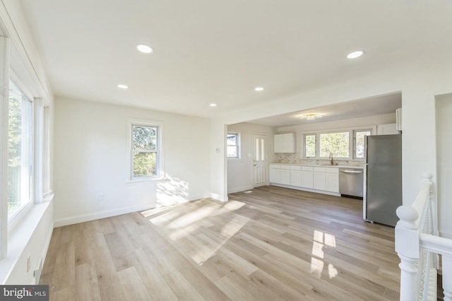 unfurnished living room with light hardwood / wood-style flooring and sink