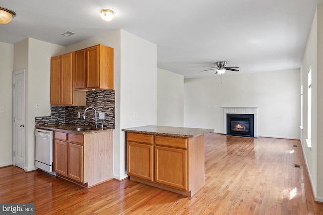 kitchen with tasteful backsplash, light hardwood / wood-style flooring, white dishwasher, and sink