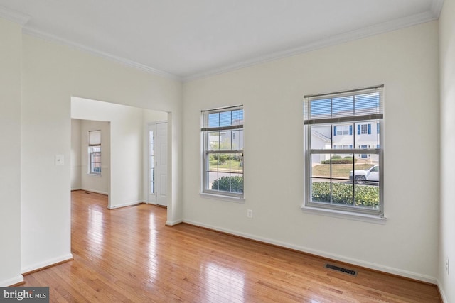 empty room with crown molding and light hardwood / wood-style flooring