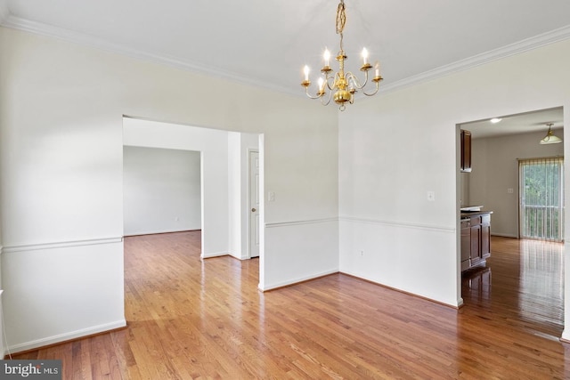 unfurnished room with an inviting chandelier, crown molding, and light hardwood / wood-style flooring