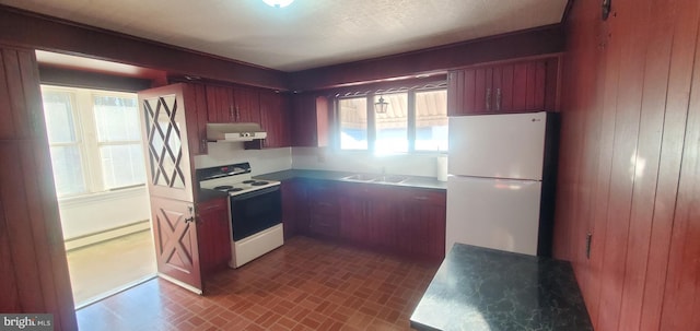 kitchen featuring white appliances, wooden walls, a baseboard heating unit, and sink