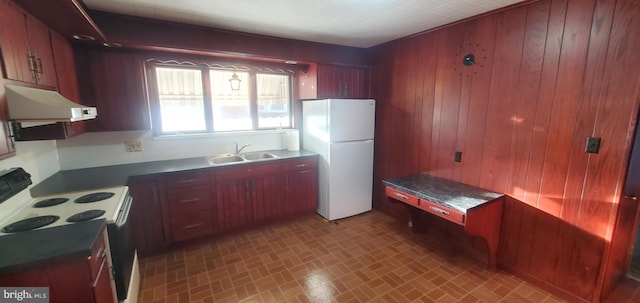 kitchen featuring wood walls, sink, and white appliances