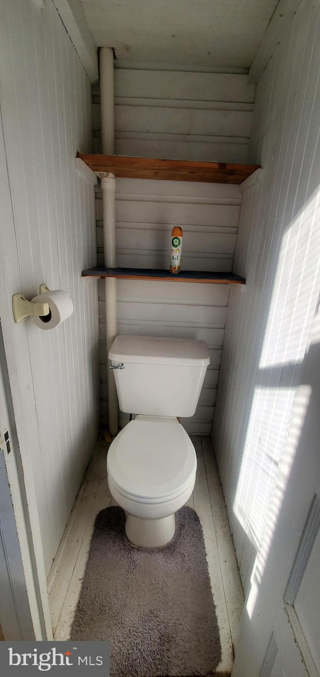 bathroom with toilet and wood walls