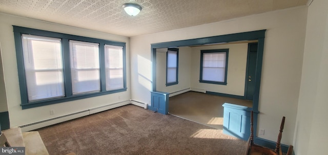 carpeted empty room with baseboard heating and a textured ceiling